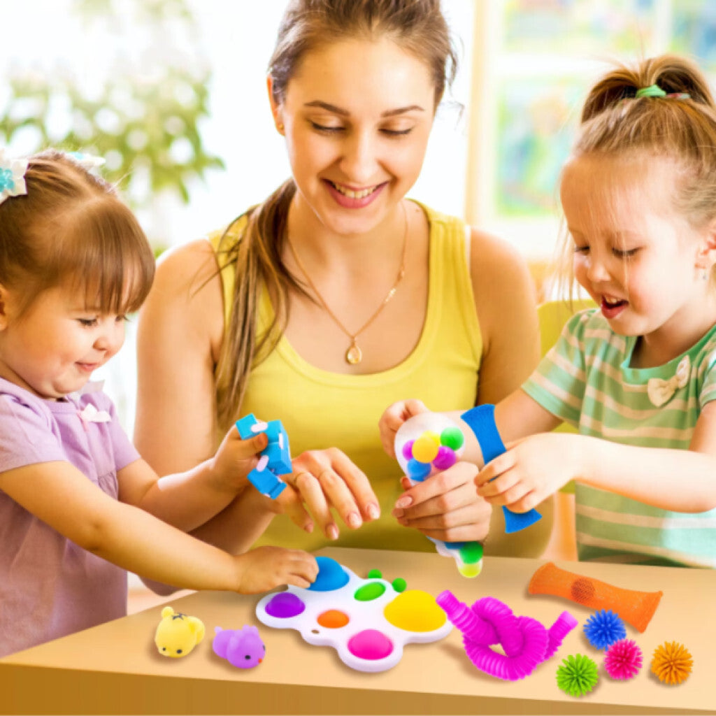 Mamă și două fetițe se joacă la masă cu jucării pop it și jucării fidget extensibile colorate