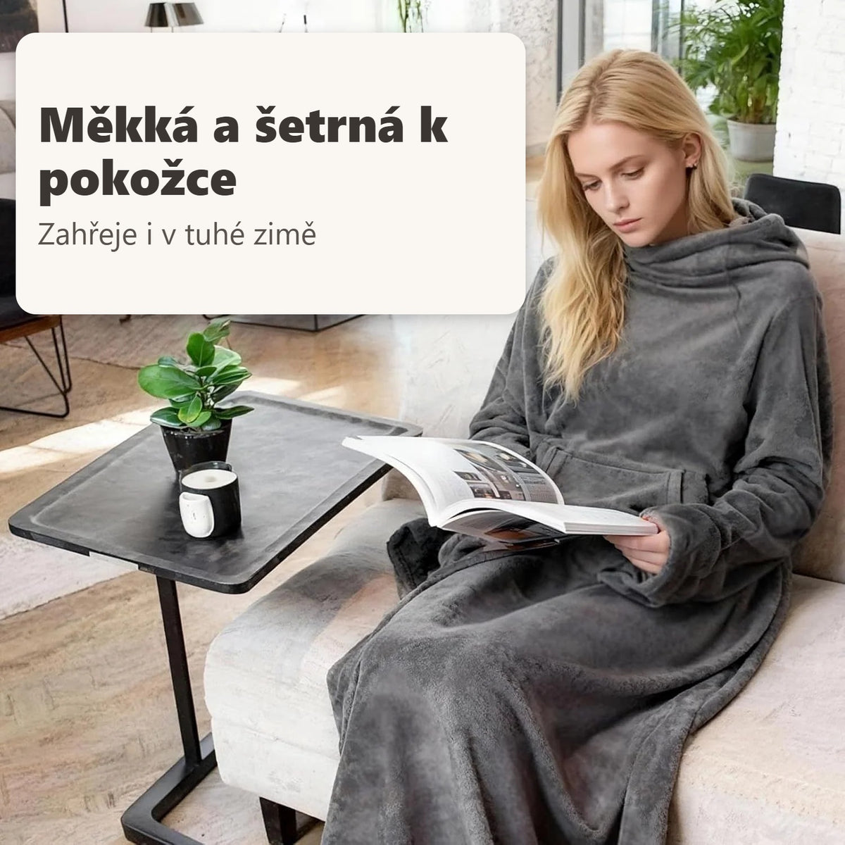 Blondýnka čte zabalená v šedé TV dece u gauče