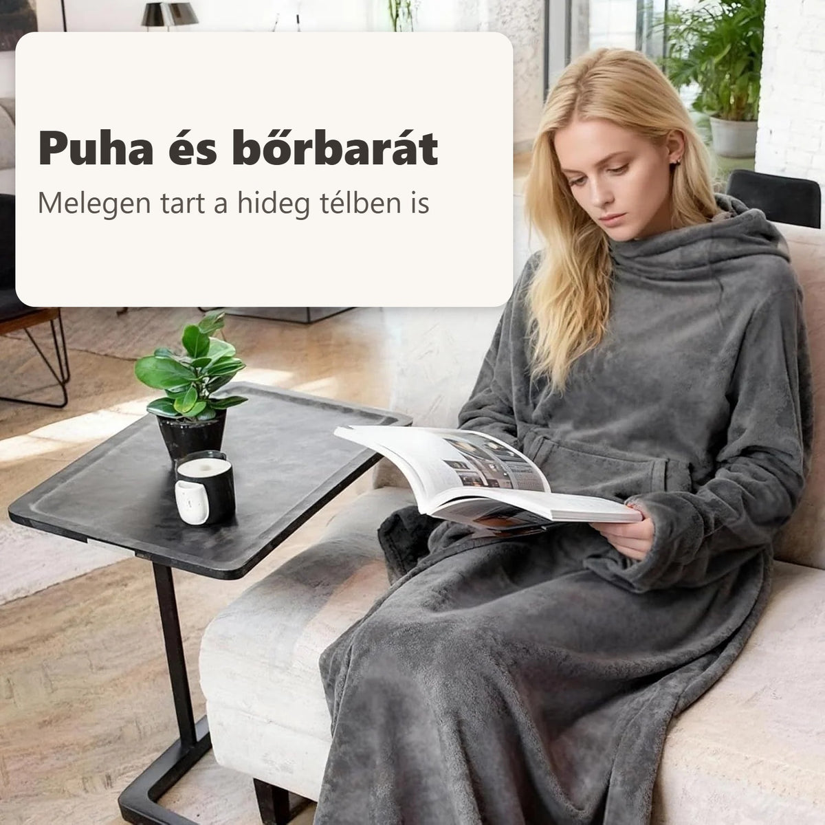Szőke nő szürke TV-takaróban olvas a kanapé mellett