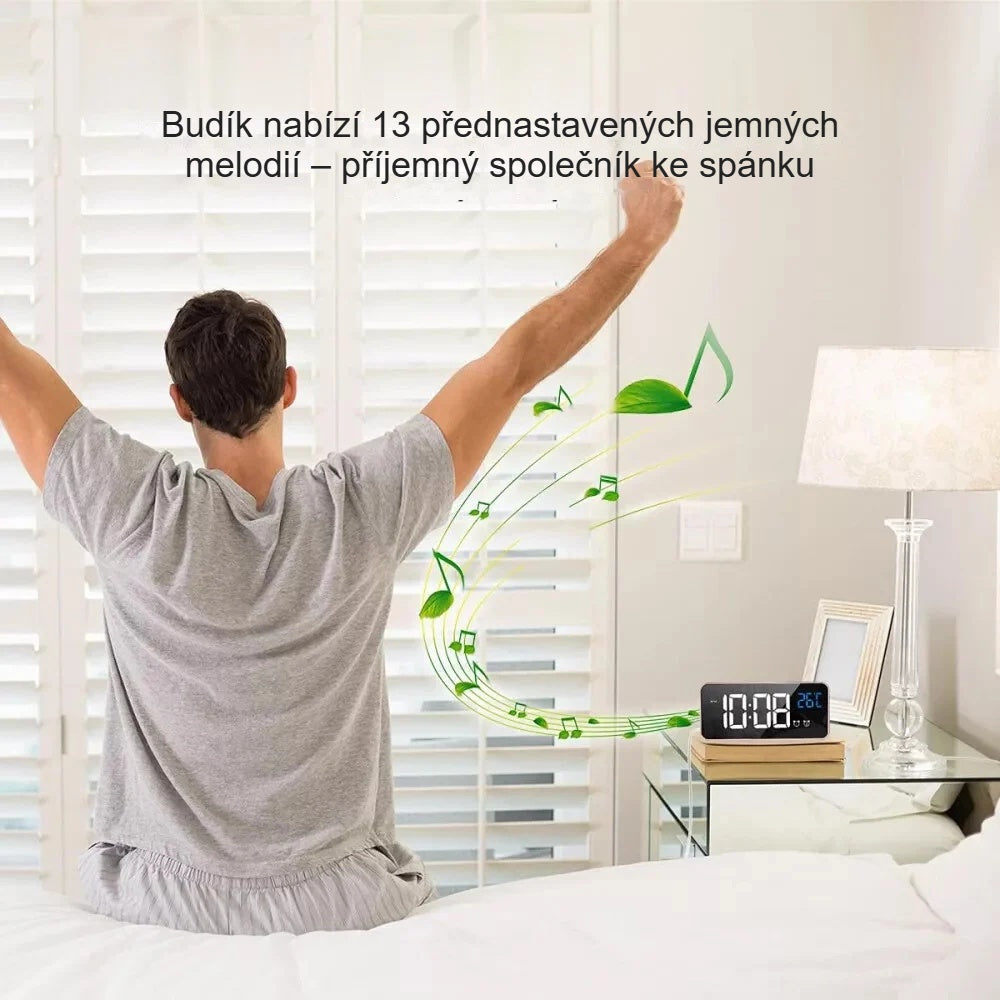 Muž se protahuje v posteli po probuzení, vedle něj budík