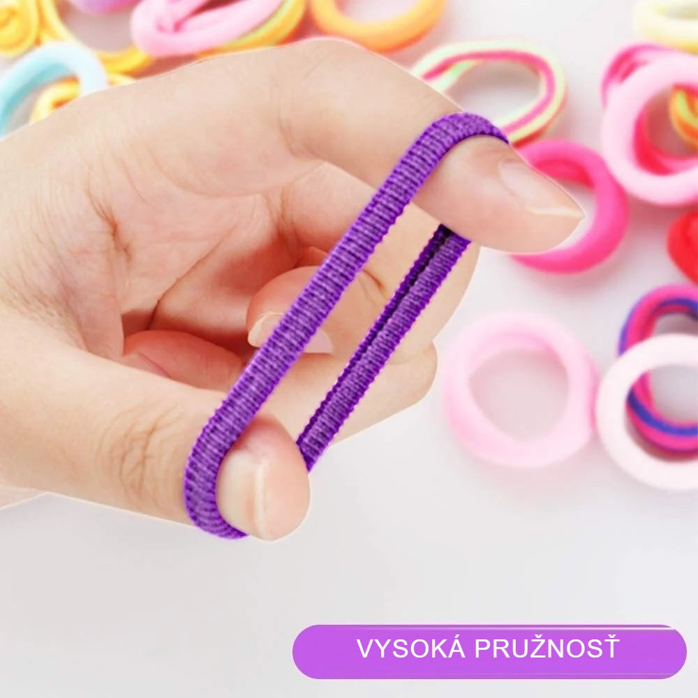 Fialová mini gumička roztiahnutá medzi prstami, ukážka pružnosti
